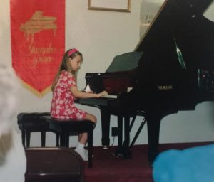 playing the grand piano at a piano recital as a child