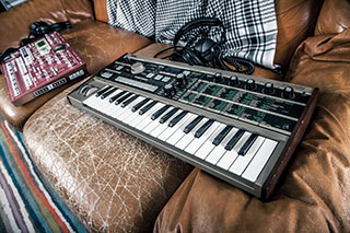 MIDI keyboard with a mixer sitting on a worn leather sofa