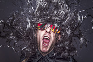 rock star with a long grey wig and crazy glasses expressing himself