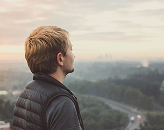 man looking into the distance over a valley at sunrise