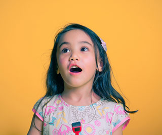 young girl excited about piano lessons while in front of a yellow background