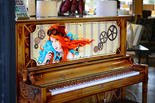 an upright piano with a woman and gears decoratively painted on the front