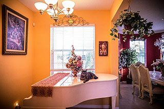 white piano in a room next to a dining room and a window